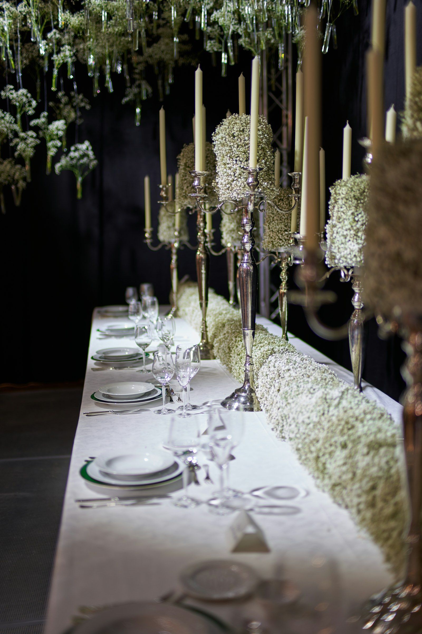 A long dinner table set with silver candelabra and white flowers
