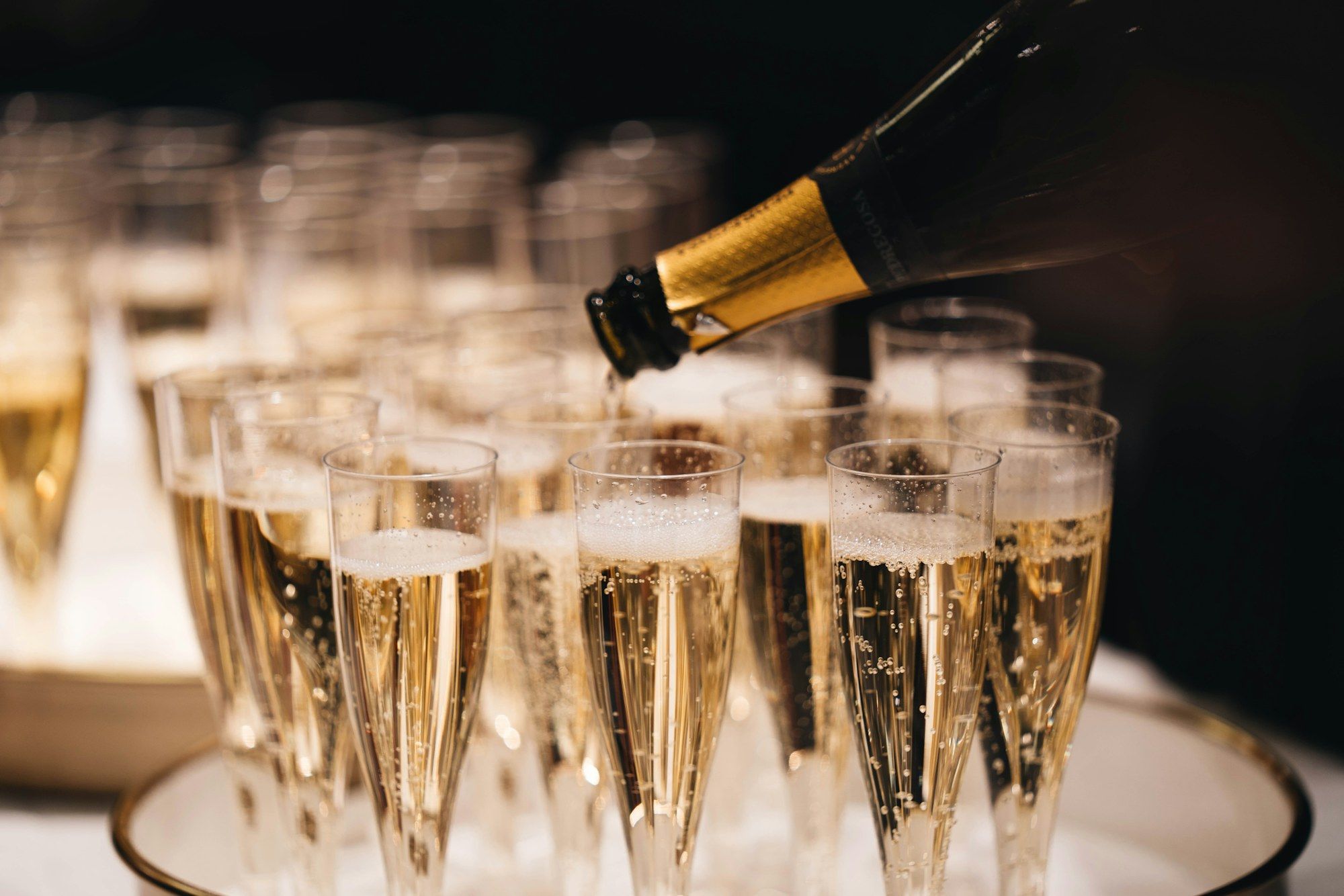 Champagne being poured into rows of flutes