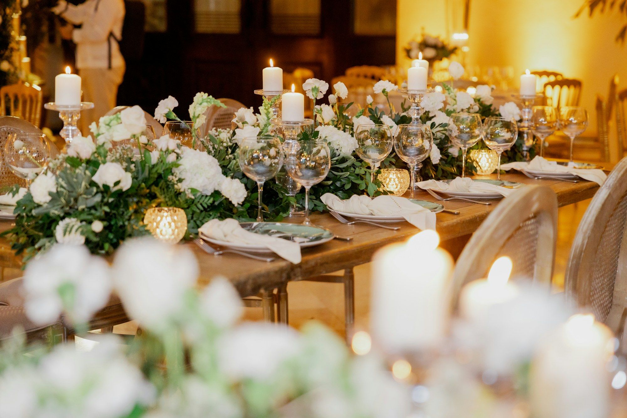 A long candlelit wedding table dressed with white flowers and crystal