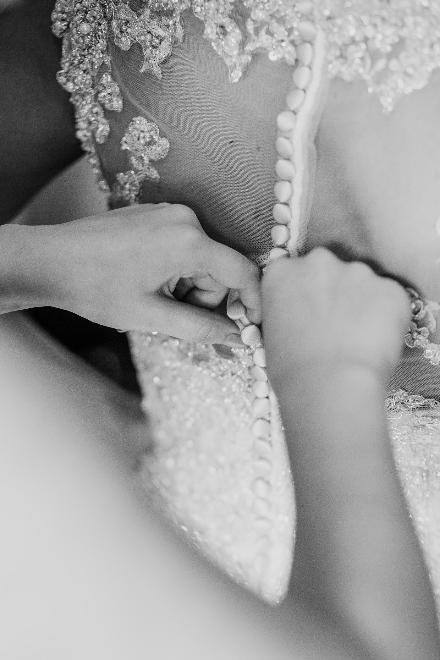 Hands fastening the buttons on the back of a wedding dress